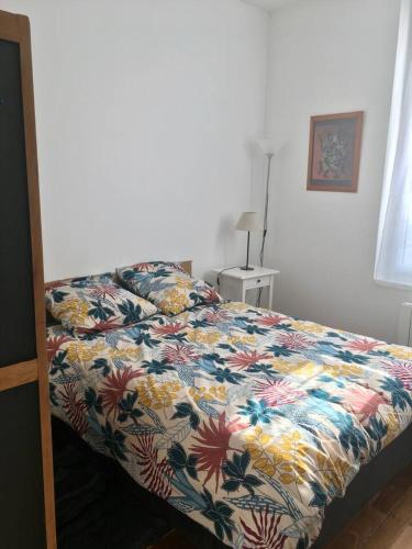 une chambre avec un lit avec un couvre-lit fleuri dans l'établissement Appartement tempéré avec terrasse, à Tours
