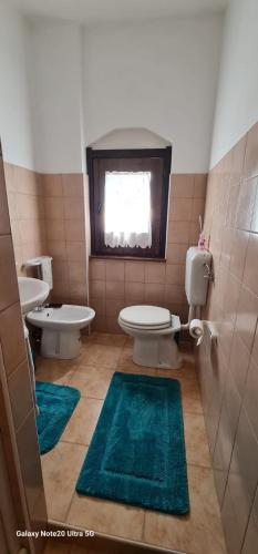 a bathroom with a toilet and a sink and two rugs at LoriCalabria-Appartamento Lorica in Lorica