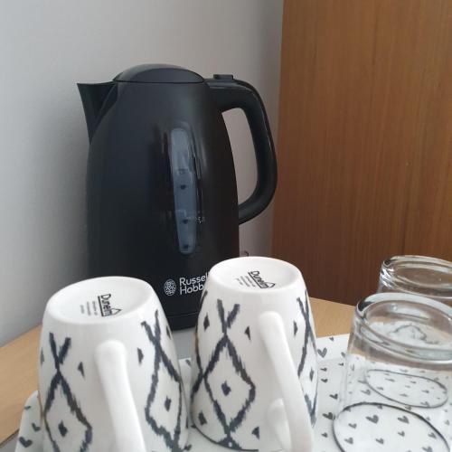 a tea pot and two mugs on a table at Canterbury Delight in Canterbury