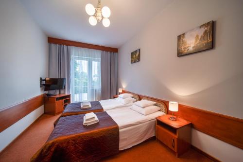 a hotel room with a bed and a television at Hotel Nad Pisą in Pisz