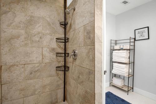 een badkamer met een douche en een stenen muur bij Hackberry Retreat - Hot Tub - Near Main in Fredericksburg