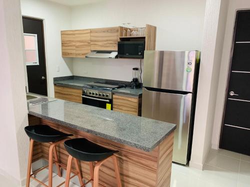 a kitchen with a refrigerator and a counter with stools at Espacioso Depto. - next to zamna TULUM in Tulum