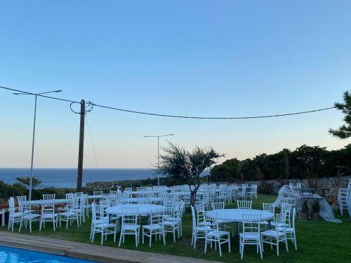 a group of tables and chairs next to a pool at Kallithea Residence in Koskinou