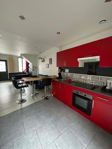 une cuisine avec des placards rouges et une table avec des chaises dans l'établissement Superbe maison 4 personnes avec Vidéo-projecteur, à Amiens