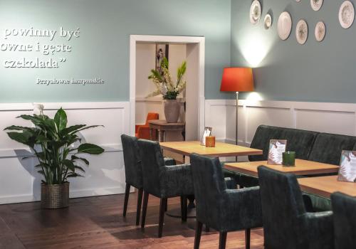 a dining room with tables and chairs and a plant at Apartamenty Sowa Toruń in Toruń