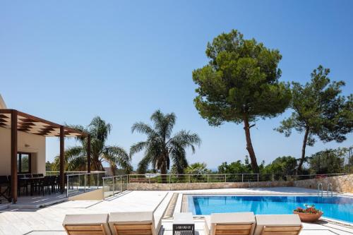 a villa with a swimming pool and palm trees at Angels Villa Chania in Kambánion