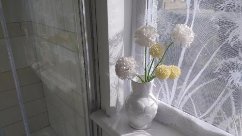 un jarrón con flores sentado en el alféizar de la ventana en Littlebeck en Danby