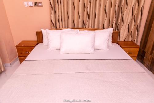 a bed with white sheets and pillows in a room at Executive Two Bedroom Apartment in Accra in Accra