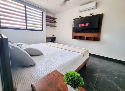 een slaapkamer met een bed en een tv aan de muur bij Home Rooftop Private Jacuzzi 3 Bedroom 4 Bth 120Mb in Xcanatún