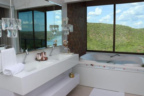 a bathroom with two sinks and a tub with a window at Pedra do Sino Hotel in Piranhas