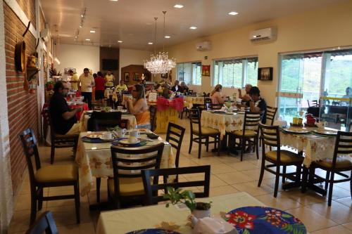 a dining room with people sitting at tables in a restaurant at Pedra do Sino Hotel in Piranhas