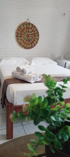 a bedroom with a bed with towels and a plant at Pousada Roane - Taíba in Taíba