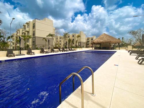 a pool at a resort with chairs and a gazebo at Espacioso Depto. - next to zamna TULUM in Tulum