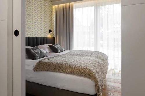 a bedroom with a bed and a large window at Tatry Mozaika Willa PREMIUM & SPA - Sauna, Jacuzzi, Flipper by RentiloPL in Zakopane
