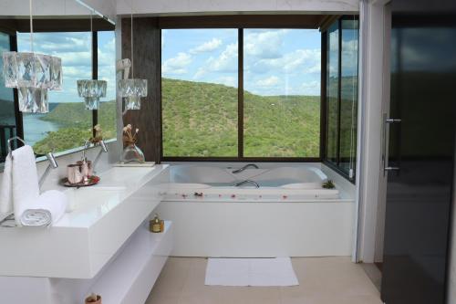 a bathroom with a tub with a large window at Pedra do Sino Hotel in Piranhas
