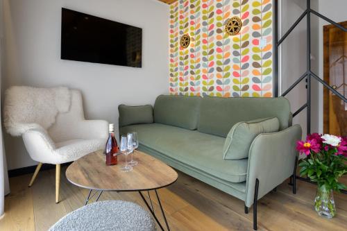 a living room with a green couch and a table at Tatry Mozaika Willa PREMIUM & SPA - Sauna, Jacuzzi, Flipper by RentiloPL in Zakopane