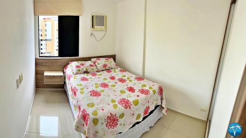 a small bedroom with a bed with a floral bedspread at Vacanze - Ametista 7 in Maceió
