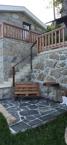 a wooden bench and a table on a stone patio at CASA DAS FONTELAS in Castelo de Paiva