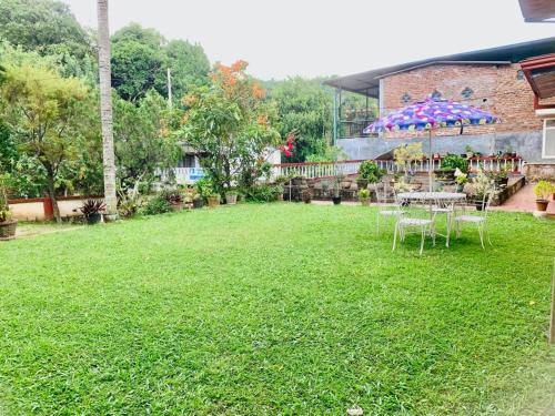 a yard with a table and chairs on the grass at Bunkhouse in Kandy