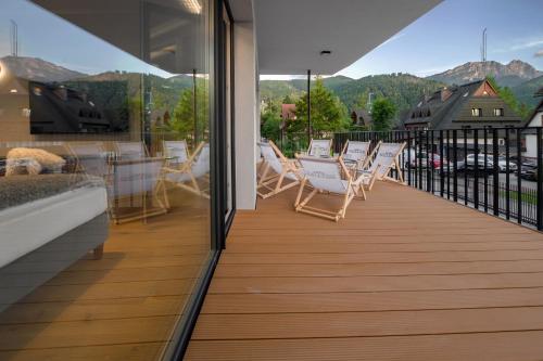 a balcony with chairs and tables with mountains in the background at Tatry Mozaika Willa PREMIUM & SPA - Sauna, Jacuzzi, Flipper by RentiloPL in Zakopane