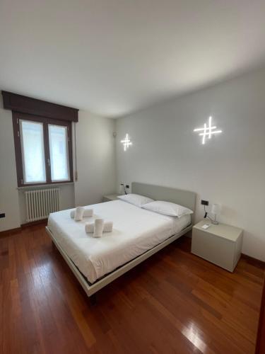 una habitación con una cama grande con sábanas y almohadas blancas en Appartamenti HERA, en Lazise