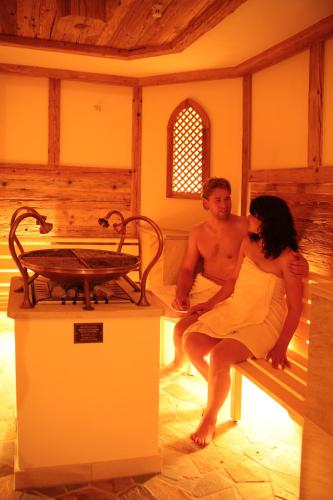 a man and a woman sitting on a bench in a room at Hotel Heselbacher Hof in Baiersbronn