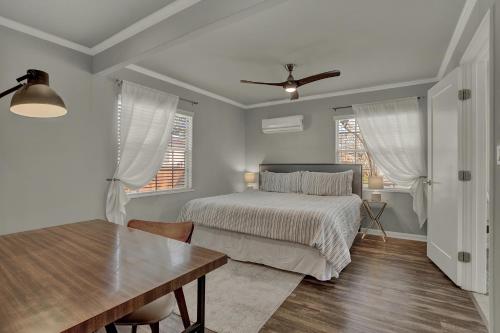 a bedroom with a bed and a table and windows at Luxury Mid Century Charmer Near Historic Main St in Fredericksburg