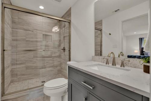a bathroom with a shower and a toilet and a sink at Luxury Haus - GREAT Backyard, Firepit, Bocce Ball! in Fredericksburg