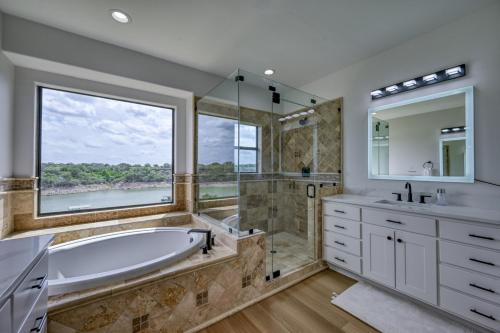 a large bathroom with a tub and a large window at Luxury Lakefront Home-Private Dock - Dipping Pool! in Spicewood