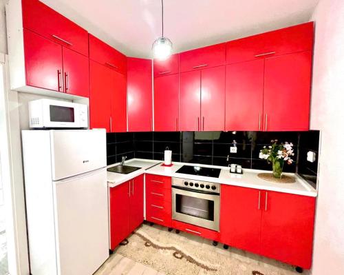 a red kitchen with white appliances and red cabinets at Apartment Adel in Mostar