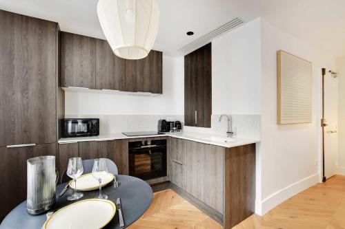 une cuisine avec des armoires en bois et une table avec des chaises dans l'établissement Élégant studio pour 2 personnes - Opéra Garnier, à Paris
