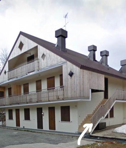 ein Gebäude mit einem Balkon und einer Treppe darauf in der Unterkunft La casa di Pianca 2.0 in Piancavallo