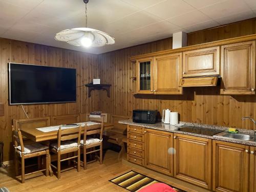 uma cozinha com armários de madeira, uma mesa e uma televisão em La casa di Pianca 2.0 em Piancavallo