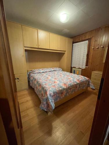 a bedroom with a bed and wooden floors and cabinets at La casa di Pianca 2.0 in Piancavallo