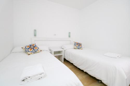 two twin beds in a room with white walls at Relaxing Apartment with Ocean Views in Puerto Rico de Gran Canaria