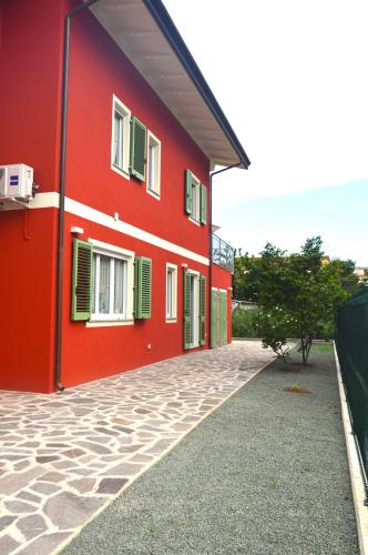a red building with green shutters on it at Rondine di Mare in Fiumaretta di Ameglia