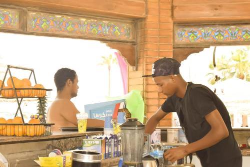 洪加達的住宿－Mashrabiya Hotel，站在厨房准备食物的人