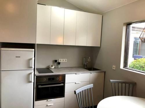 La cuisine est équipée de placards blancs et d'un réfrigérateur blanc. dans l'établissement Adorable one bedroom apartment with free parking., à Reykjavik