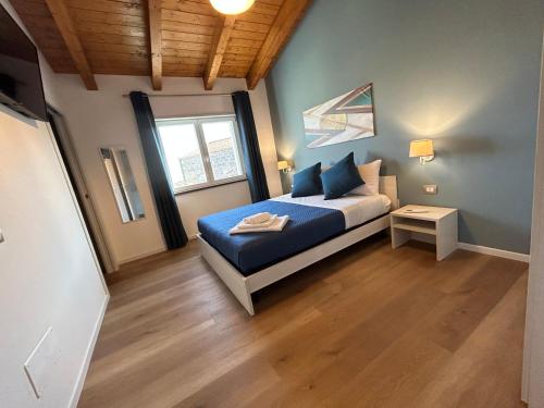 a bedroom with a bed with blue sheets and a window at Ferdinando’s House in Pozzomaggiore