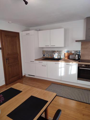 une cuisine avec des armoires blanches et une table en bois dans l'établissement Confortable appartement au centre de Sélestat, à Sélestat