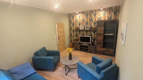 a living room with two blue chairs and a television at Zielono mi....... in Jelenia Góra