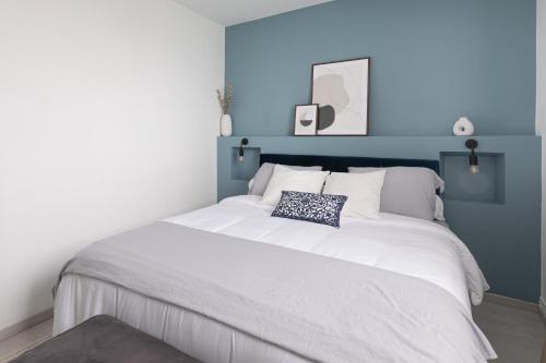 1 dormitorio con 1 cama blanca grande y paredes azules en Mat&Ness Appartment en Beauvais