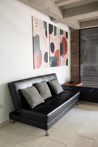 a black leather couch in a room with paintings on the wall at M1145 Aparta Loft in Pereira