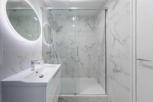 y baño blanco con lavabo y ducha. en Mat&Ness Appartment en Beauvais