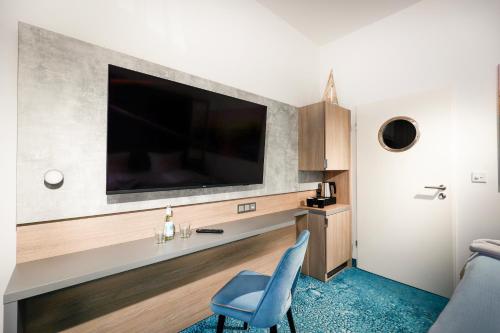 a living room with a tv and a blue chair at Hotel Leuchtturm in Timmendorfer Strand