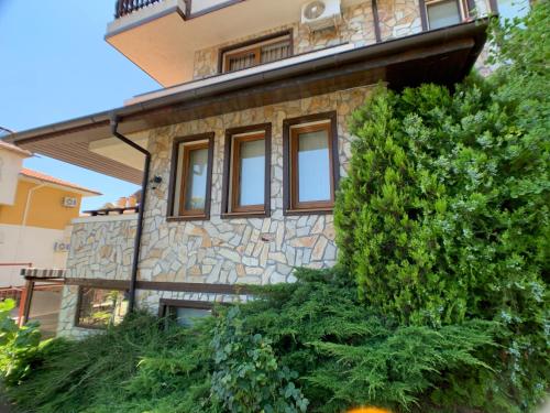 a stone house with windows and a bush at Garden studio Kent in Sveti Vlas