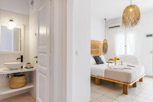 a white bedroom with a bed and a sink at Ourania Studios & Apartments in Skopelos Town