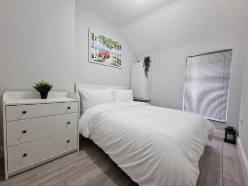 a white bedroom with a white bed and a dresser at Modern Belfast City Home in Belfast
