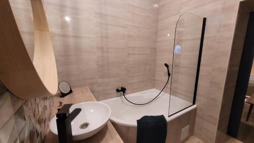 a bathroom with a white sink and a shower at Glamour Apartman in Gyula