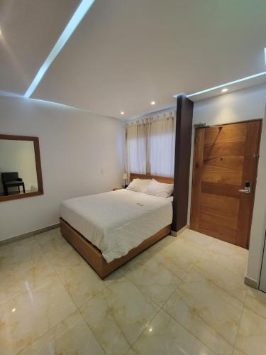 a bedroom with a bed and a wooden door at Marcel Suites in Santo Domingo